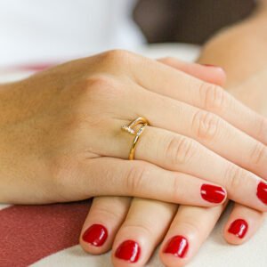 Mãos femininas com unhas vermelhas exibindo anel; destaque para atacadista eletrônicos no Produto.